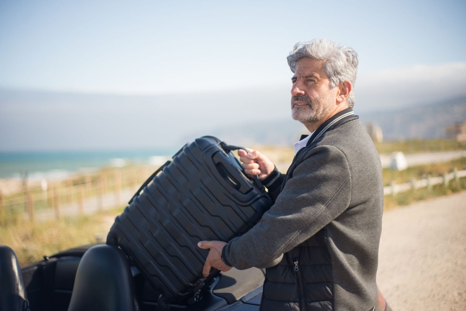 Man lifting a travel case into a car